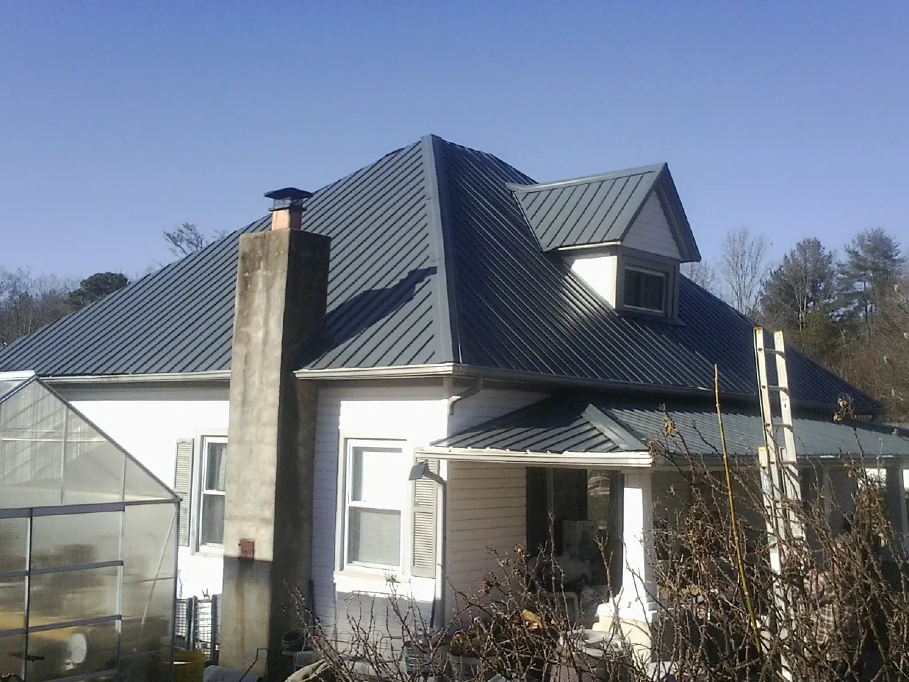 Dark blue standing seam metal roof on a white farmhouse with dormer — Slate & Tile Roof Repair by Roofing Brothers in Little Ferry