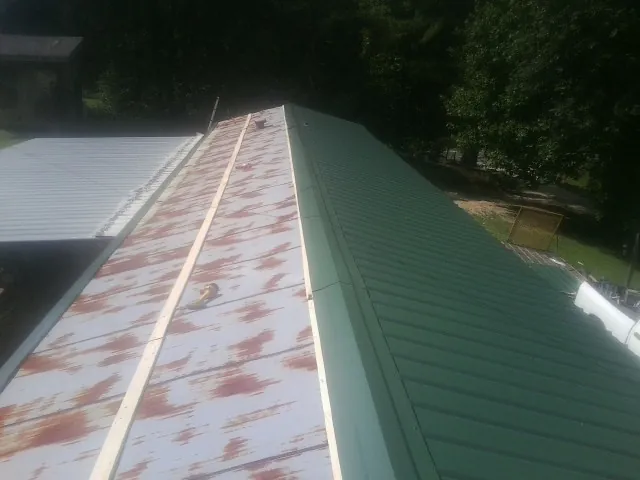 Old rusted panels beside newly installed green metal roofing — Wind Damage Roof Repair by Roofing Brothers in Little Ferry