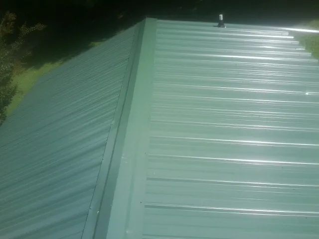 New green metal panels meeting at the ridge of a roof — Flat Roof Repair work by our crew in Little Ferry