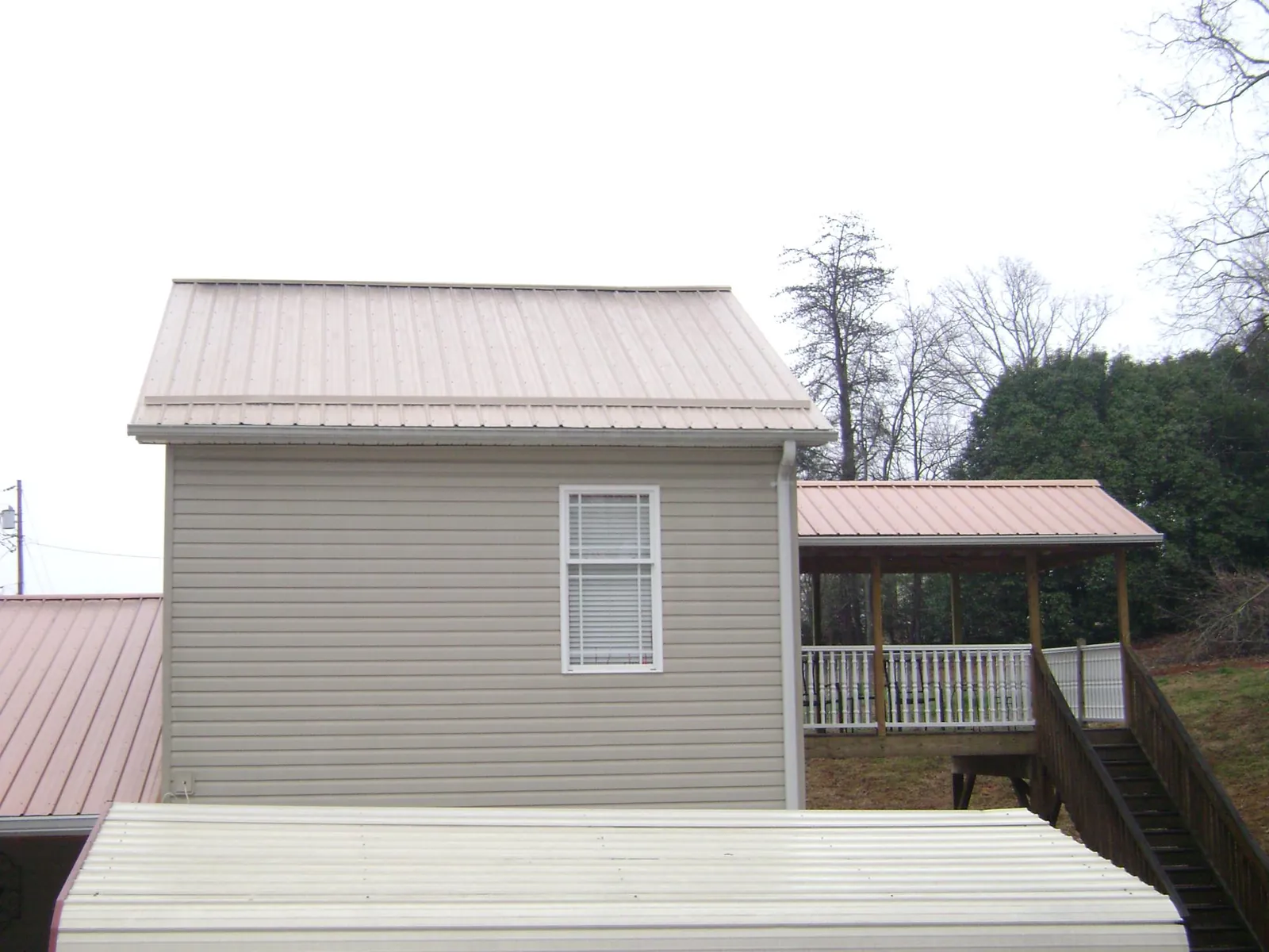 Tan metal roofs on a two story addition and attached porch, from a Roof Replacement job in Little Ferry