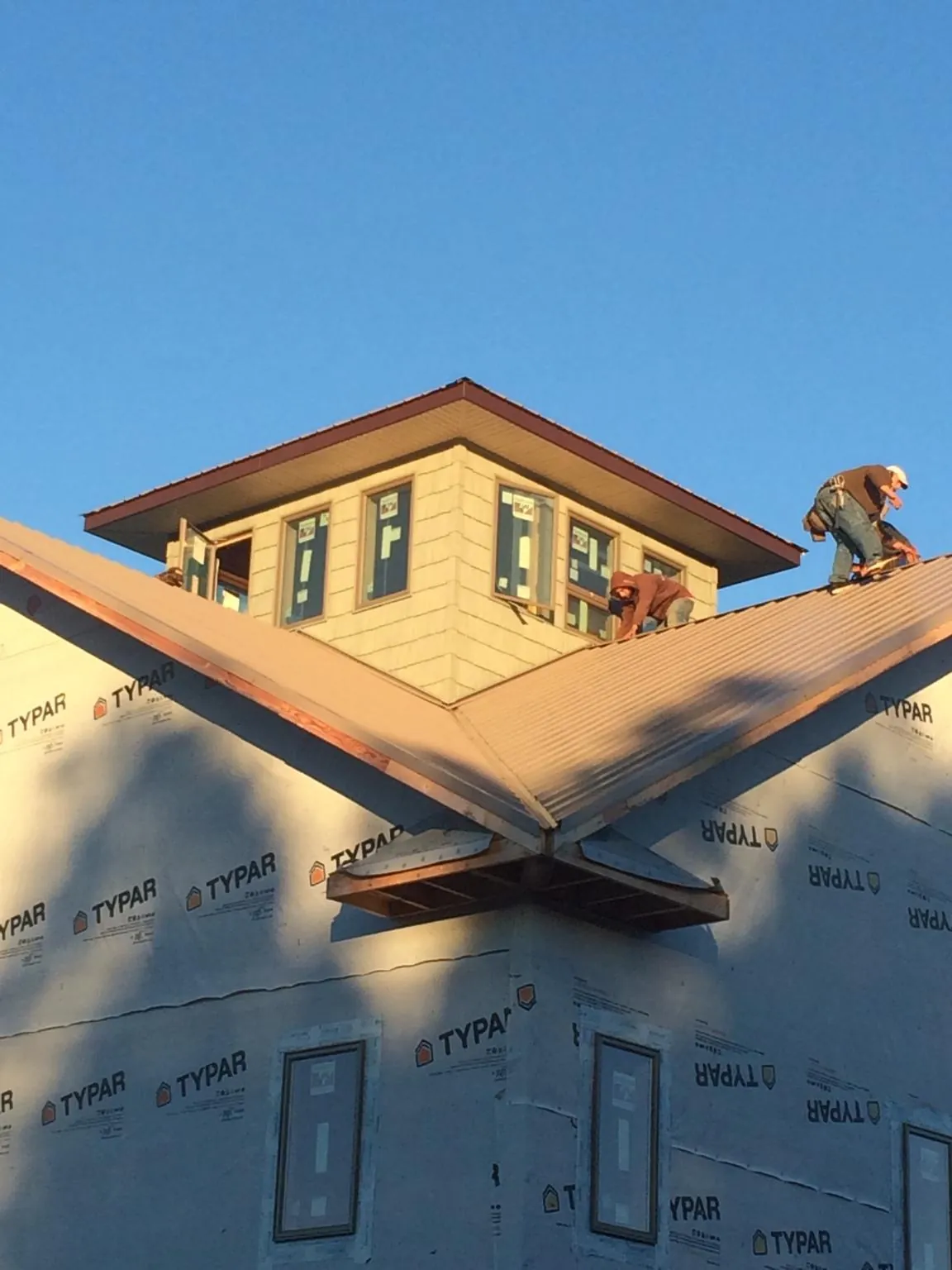 Roofers working around a rooftop cupola on a new metal roof at sunset — Roof Waterproofing in Little Ferry by Roofing Brothers